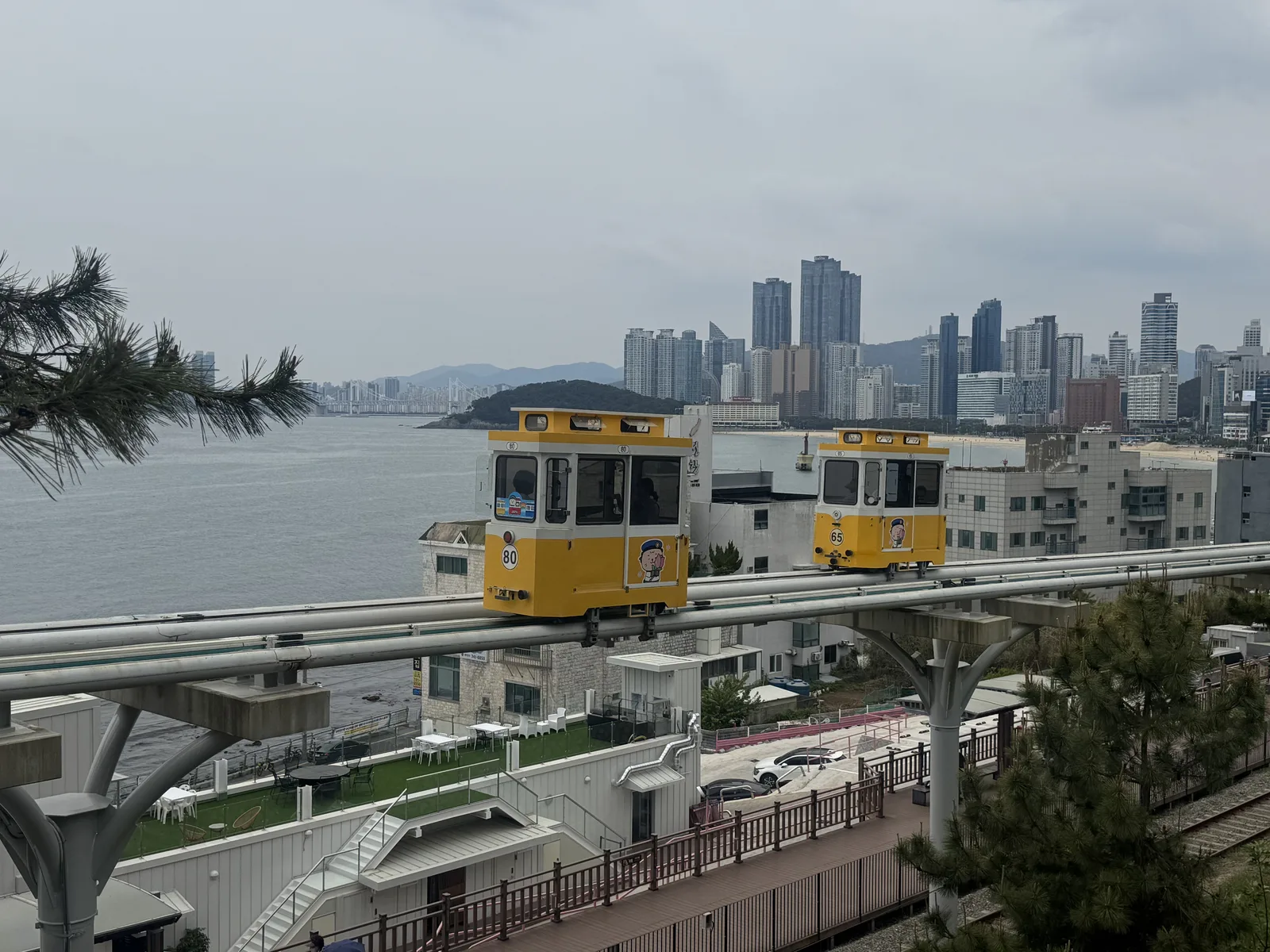 Cabines coloridas do Sky Capsule sobre trilhos elevados junto ao mar em Haeundae